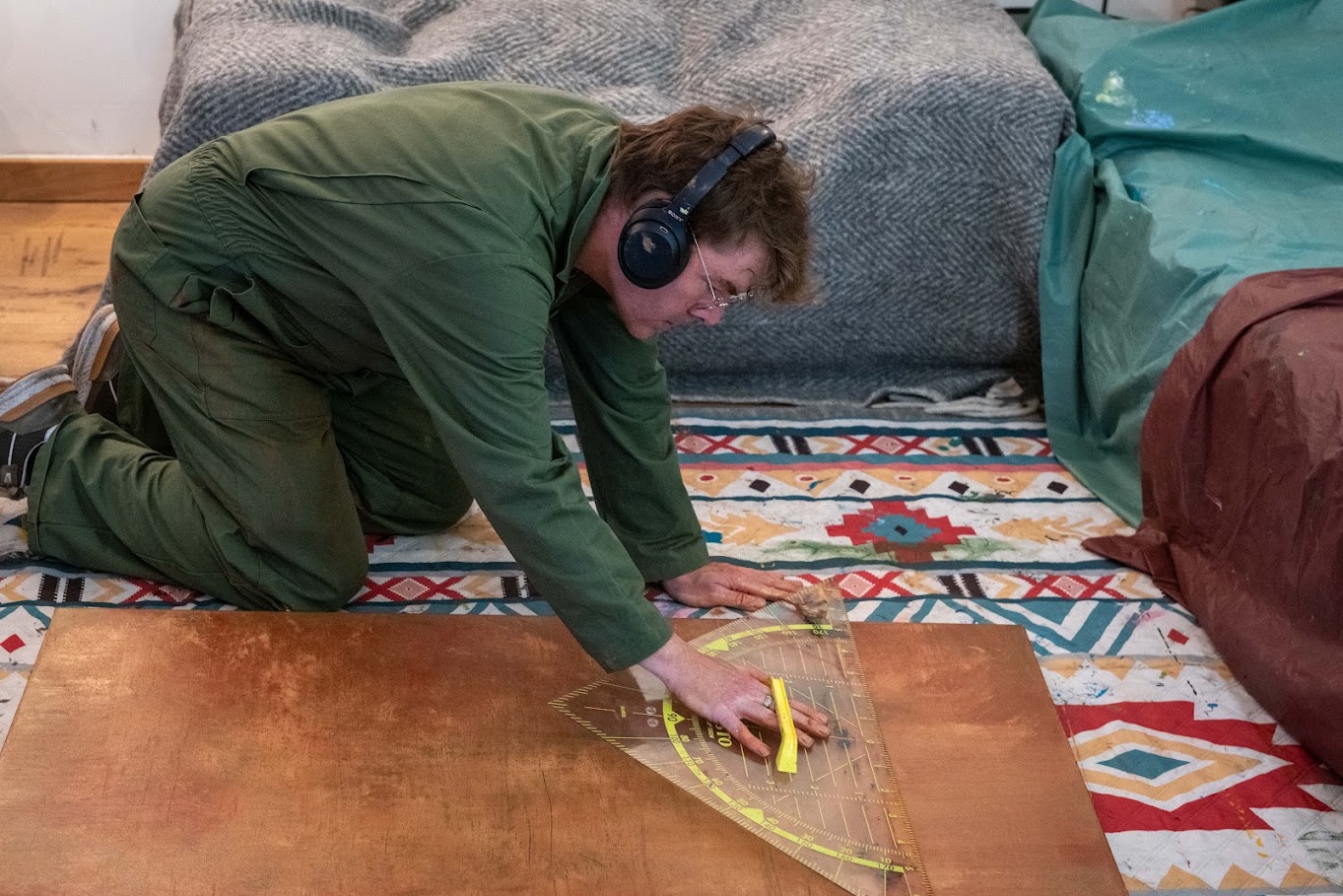 Ward Schepman, wearing headphones, drawing lines on a canvas with a triangular ruler and pencil.